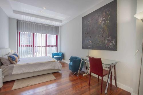 Dormitorio con cama, escritorio y pintura en Chueca Gran Via Recoletos Libertad 24 4 en Madrid