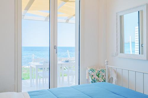 a bedroom with a bed and a view of the ocean at La fuga blu di Marzamemi in Marzamemi