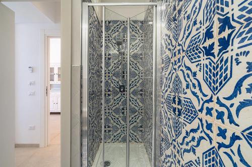 a glass shower with a blue and white wall at La fuga blu di Marzamemi in Marzamemi