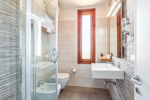 ein Bad mit einem Waschbecken, einem WC und einer Dusche in der Unterkunft Hotel Agugliastra in Santa Maria Navarrese