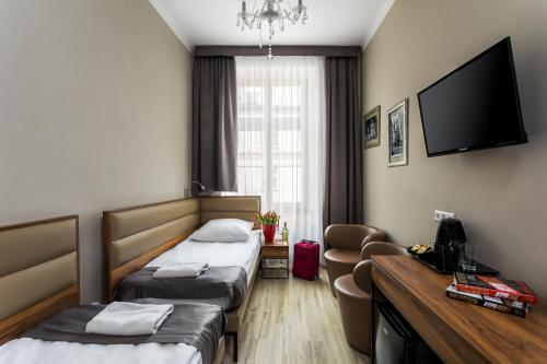 a hotel room with two beds and a flat screen tv at Grodzka Royal Apartments in Krakow