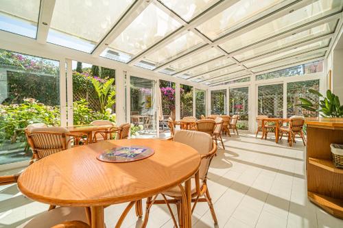 a conservatory with tables and chairs and windows at Hotel Yacht Club in Marciana Marina