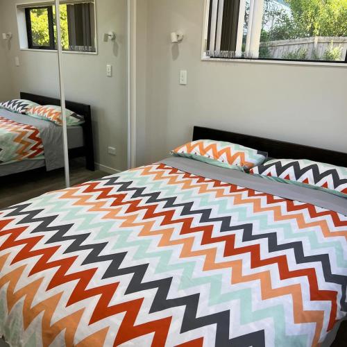 a bedroom with a bed with an orange and white comforter at Beautiful 2 Bedroom Home in Auckland