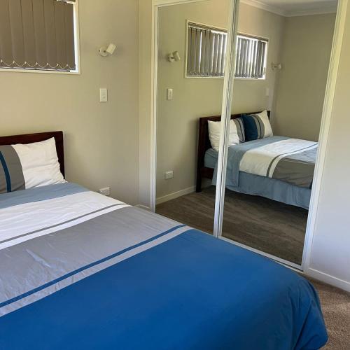 a bedroom with two beds and a mirror at Beautiful 2 Bedroom Home in Auckland