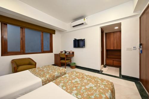 a hotel room with two beds and a television at Hotel Parle International in Mumbai