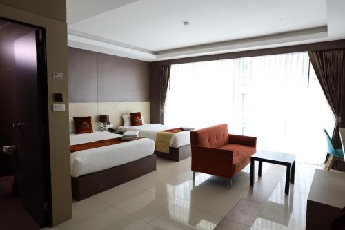 パタヤ・ノースにあるGranDE Classic Pattayaのベッド2台と椅子があるホテルの部屋