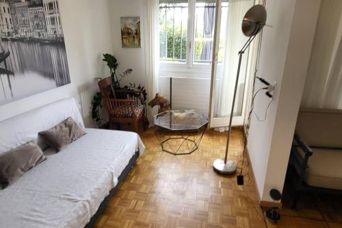 een slaapkamer met een wit bed en een vloerlamp bij Lake side(5min)/fire place/garden/freeparking/45m2 in La Tour-de-Peilz