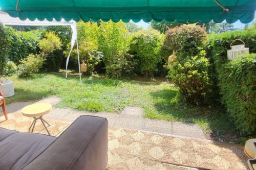 een patio met een bank, een tafel en een parasol bij Lake side(5min)/fire place/garden/freeparking/45m2 in La Tour-de-Peilz