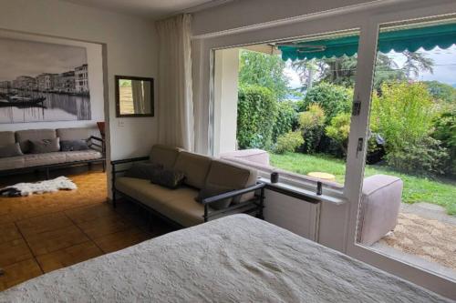 een slaapkamer met een bank en een groot raam bij Lake side(5min)/fire place/garden/freeparking/45m2 in La Tour-de-Peilz