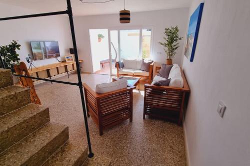 a living room with a couch and chairs and stairs at La Tejita Holiday House in La Tejita