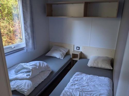 Camping 4 étoiles DOMAINE D'EUROLAC في Aureilhan: سريرين في غرفة صغيرة مع نافذة