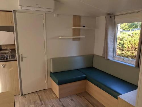 Cette petite chambre dispose d'un banc bleu et d'une fenêtre. dans l'établissement Camping 4 étoiles RIVAGES DES LANDES anciennement Domaine Eurolac, à Aureilhan
