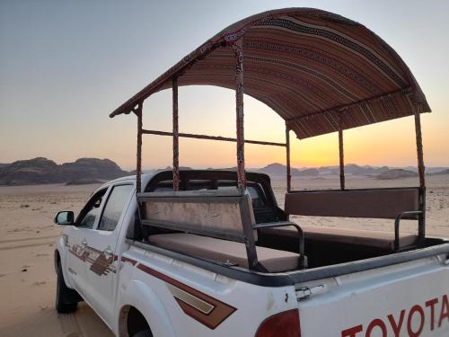 a white pickup truck with an umbrella on the back at rum rema camp in Wadi Rum