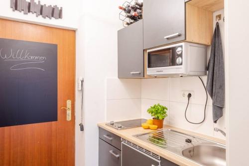 a small kitchen with a sink and a microwave at Stilvolles Appartement im lässigsten Viertel in Munich