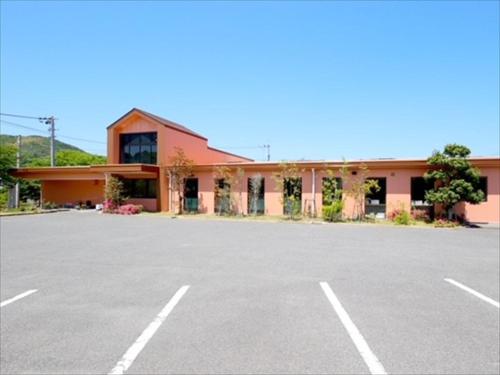 a large parking lot in front of a pink building at I-Link Hostel & Cafe Shimanami in Imabari
