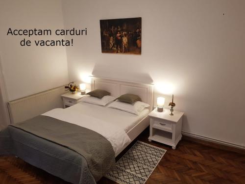 Un dormitorio con una cama con dos mesitas de noche y dos mesas. en Casa Milan, en Oradea