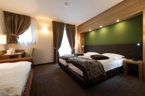 a hotel room with two beds and a green wall at Hotel Vedig in Santa Caterina Valfurva