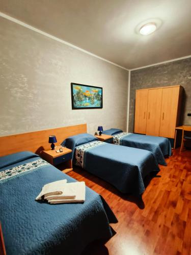 a hotel room with three beds with blue sheets at AFFITTACAMERE DOLCE SOGNO in Cherasco