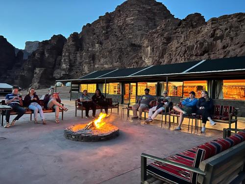 eine Gruppe von Menschen, die um eine Feuerstelle herum sitzen in der Unterkunft Wadi Rum Bedouin Camp in Wadi Rum