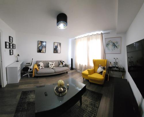 uma sala de estar com um sofá e uma cadeira amarela em Your home from home em Londres