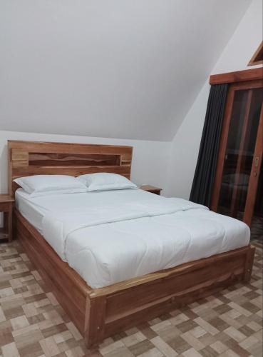 a bedroom with a large bed with white sheets at Popitan Garden Campground & Glamping Bedugul in Bedugul