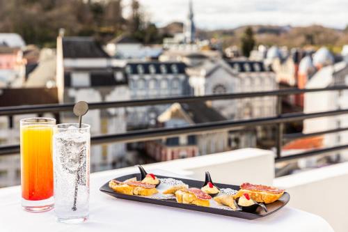 a plate of food on a table with a drink at Mercure Lourdes Impérial in Lourdes