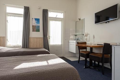 a hotel room with two beds and a desk and a kitchen at Hotelletje de Veerman in Oost-Vlieland