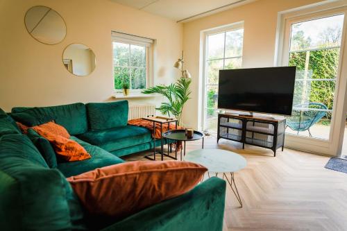 a living room with a green couch and a flat screen tv at Luxe Veluws Vakantiehuis met JACUZZI in Lunteren