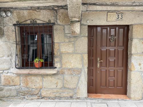 um edifício de pedra com uma porta castanha e uma janela em A Casiña de Juan em Corcubión