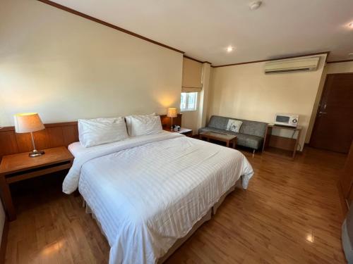a bedroom with a large white bed and a living room at Jhouse Thonglor in Khlong Toei