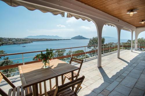 d'une terrasse avec une table, des chaises et l'eau. dans l'établissement Phaedrus Living Sea View Villa Aegina, à Perdika