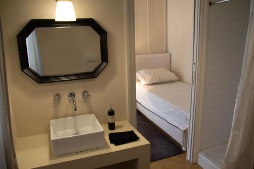 a bathroom with a sink and a mirror and a bed at La Maison du Théâtre in Ravenna