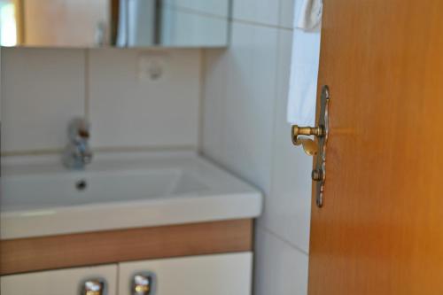 ein Badezimmer mit einem Waschbecken und einer Holztür in der Unterkunft Hotel Adler in Lauda-Königshofen