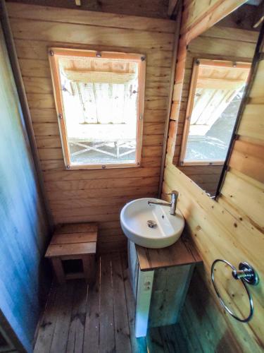 a bathroom with a sink and a window in a log cabin at Camping la Grangeonne in Esparron-de-Verdon