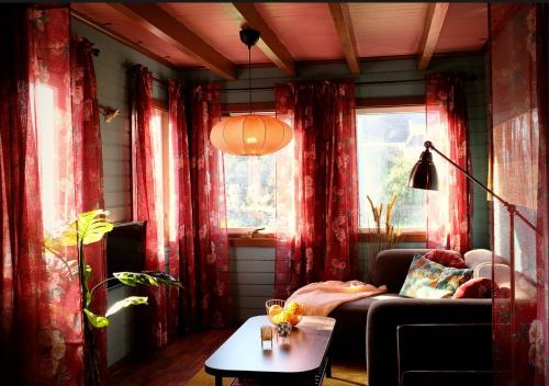 sala de estar con cortinas rojas, sofá y mesa en Lunvig Romantic country house by the sea in Kristiansand, Søgne, en Kristiansand