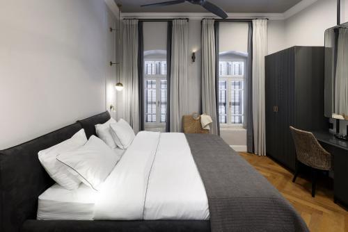 a bedroom with a large white bed and two windows at Allegro Neve Tzedek Boutique Suites - By HOMY in Tel Aviv