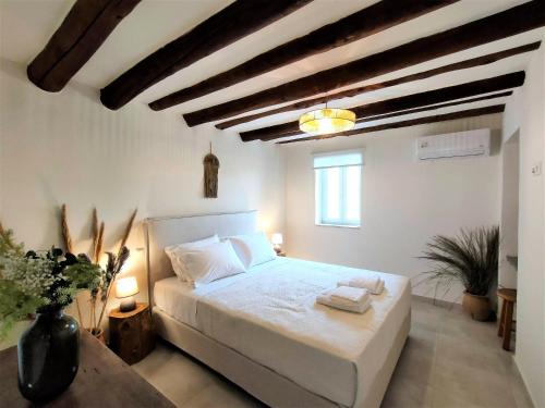 a bedroom with a white bed in a room with wooden ceilings at Spiti Sea View Neoclassical House in Stenies in Andros