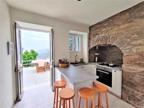 a kitchen with a stone wall and stools in it at Spiti Sea View Neoclassical House in Stenies in Andros