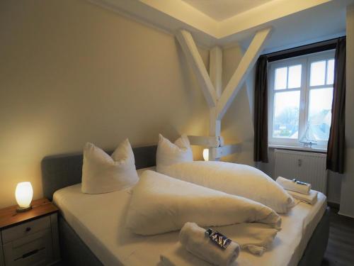 een slaapkamer met 2 bedden met witte kussens en een raam bij Villa Balticum, Whg 5 in Zingst