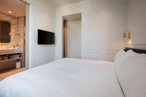 a white bedroom with a large white bed and a sink at Pillows Grand Boutique Hotel Maurits at the Park - Small Luxury Hotels in Amsterdam