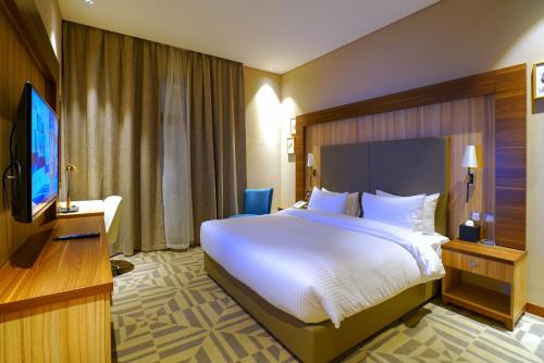 una camera d'albergo con un letto grande e una TV a schermo piatto di Al Aseel Hotel a Doha