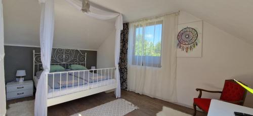 biała sypialnia z łóżeczkiem dziecięcym i oknem w obiekcie Boholand Apartman Eger w Egerze