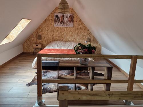 sypialnia na poddaszu z łóżkiem i stołem w obiekcie Gîte les 4 sabots de la Baie w mieście Bourseville
