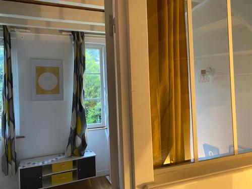 Cette chambre dispose d'un miroir et d'une fenêtre avec des rideaux jaunes. dans l'établissement La Closerie un écrin de verdure à 500m de la plage, à Sainte-Adresse