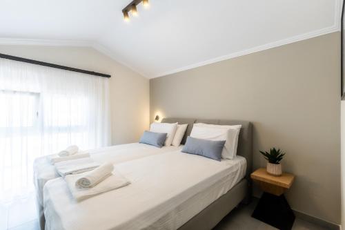 a bedroom with a large bed with white sheets and blue pillows at Bianco Mare Studios-Apartments in Kalivia Poligirou