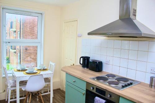 a kitchen with a stove and a table and a window at Luxury Living at Hampden Gardens - Stunning Two-Bedroom Flats from Fran Properties! in Buckinghamshire