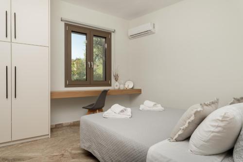 a white room with a bed and a window at Diov Bohali House in Zakynthos
