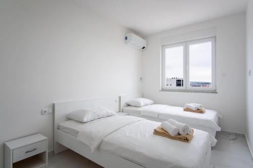 duas camas num quarto branco com toalhas em Noa East Residence em Novalja
