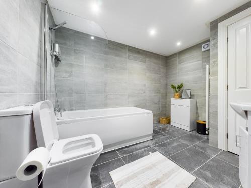 a bathroom with a white tub and a toilet at 18 Palm Hill, Oxton in Upton