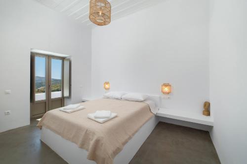 a white bedroom with a bed and a window at Villa Stefano La Fleur Andros in Andros